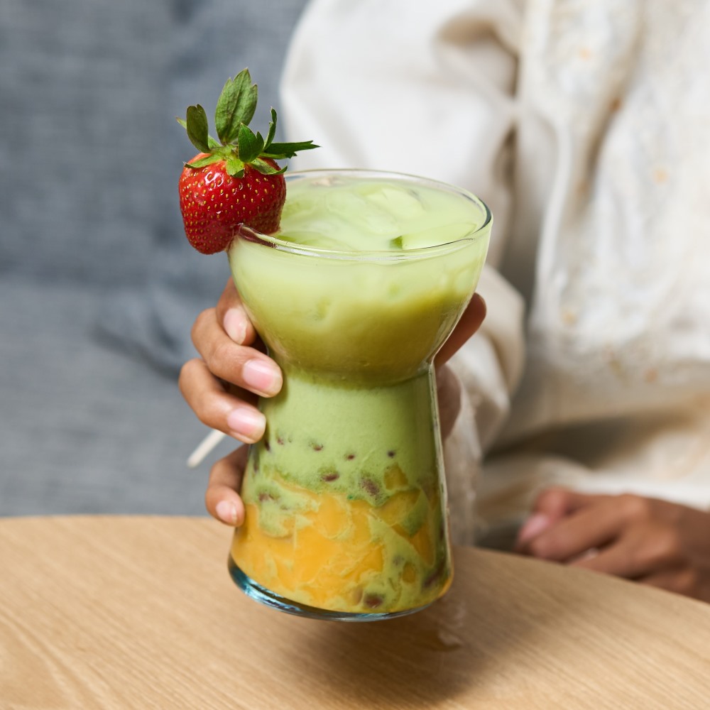 Minuman RaMadhanCha dengan lapisan matcha susu, strawberry segar, dan mango pudding yang manis dan creamy.