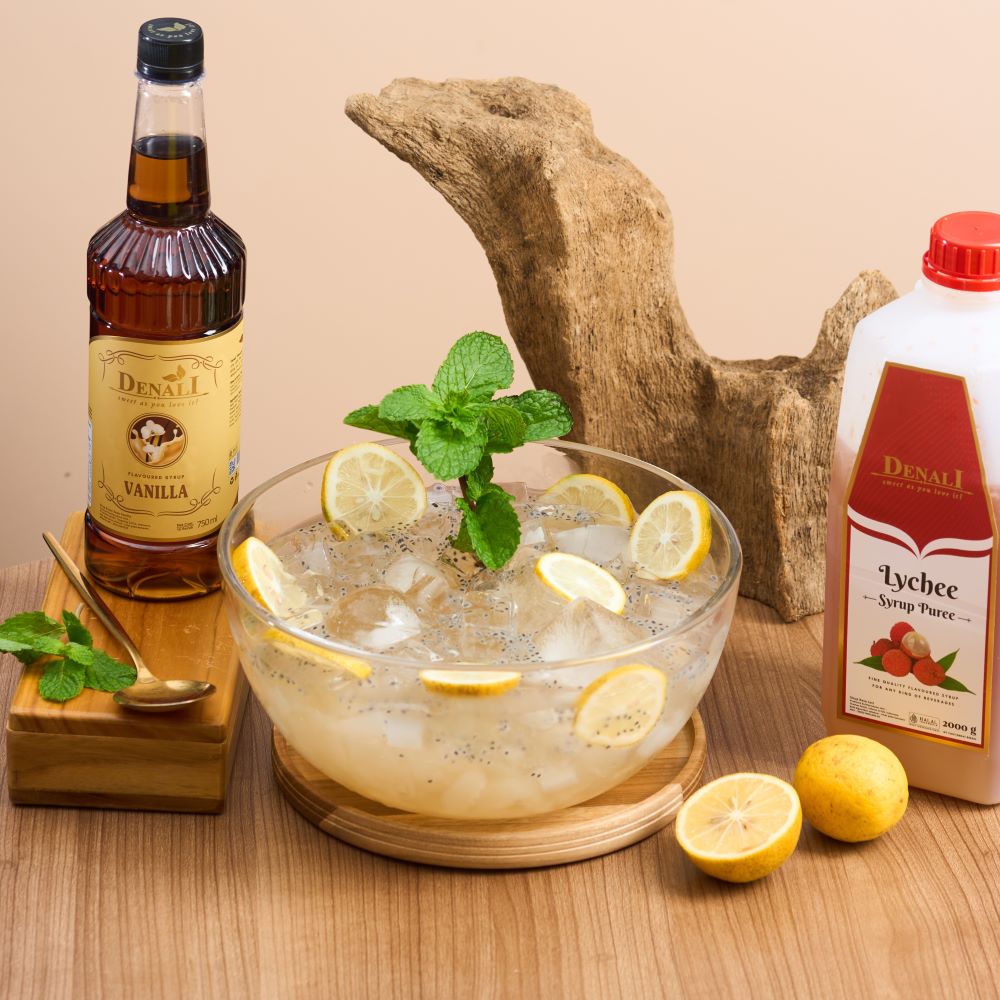 Iced Sarang Wallet Lychee dengan lychee puree, jelly kelapa, nata de coco, biji selasih, dan garnish lemon yang tampak segar dan bertekstur.