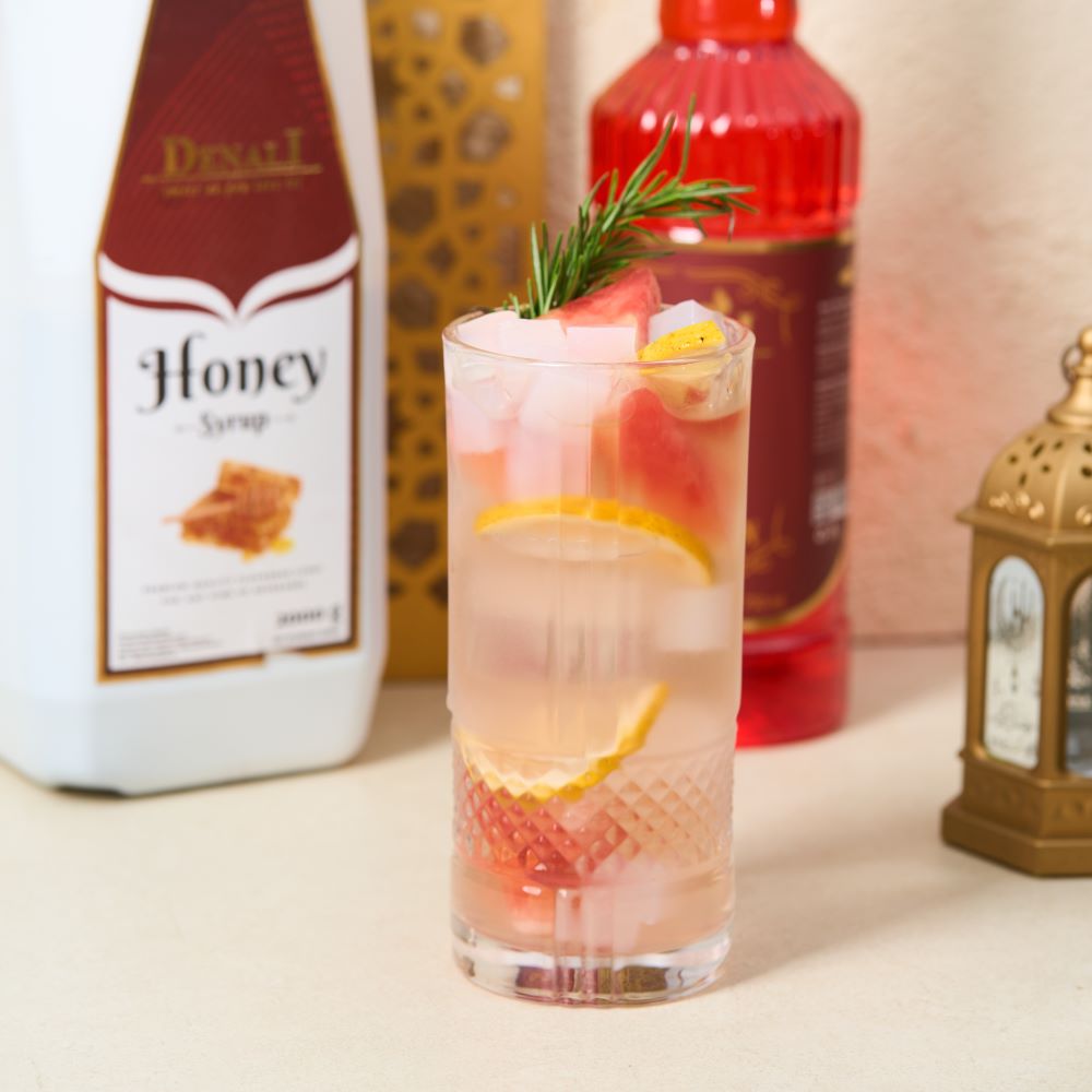 Minuman Lovely Honey berwarna merah muda segar dengan perpaduan semangka, madu, lemon, dan air kelapa yang tampak ringan dan menyegarkan.