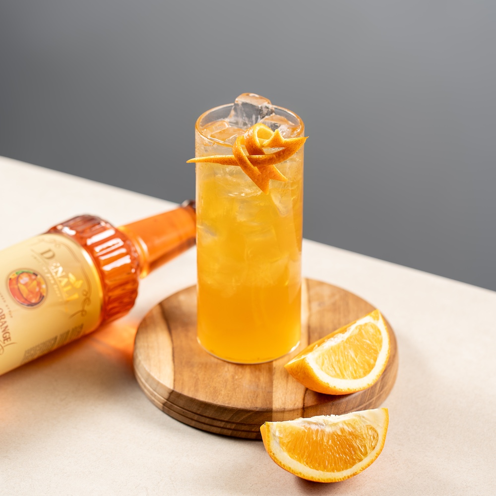 Minuman summer kuning segar dengan garnish lemon dan es batu transparan