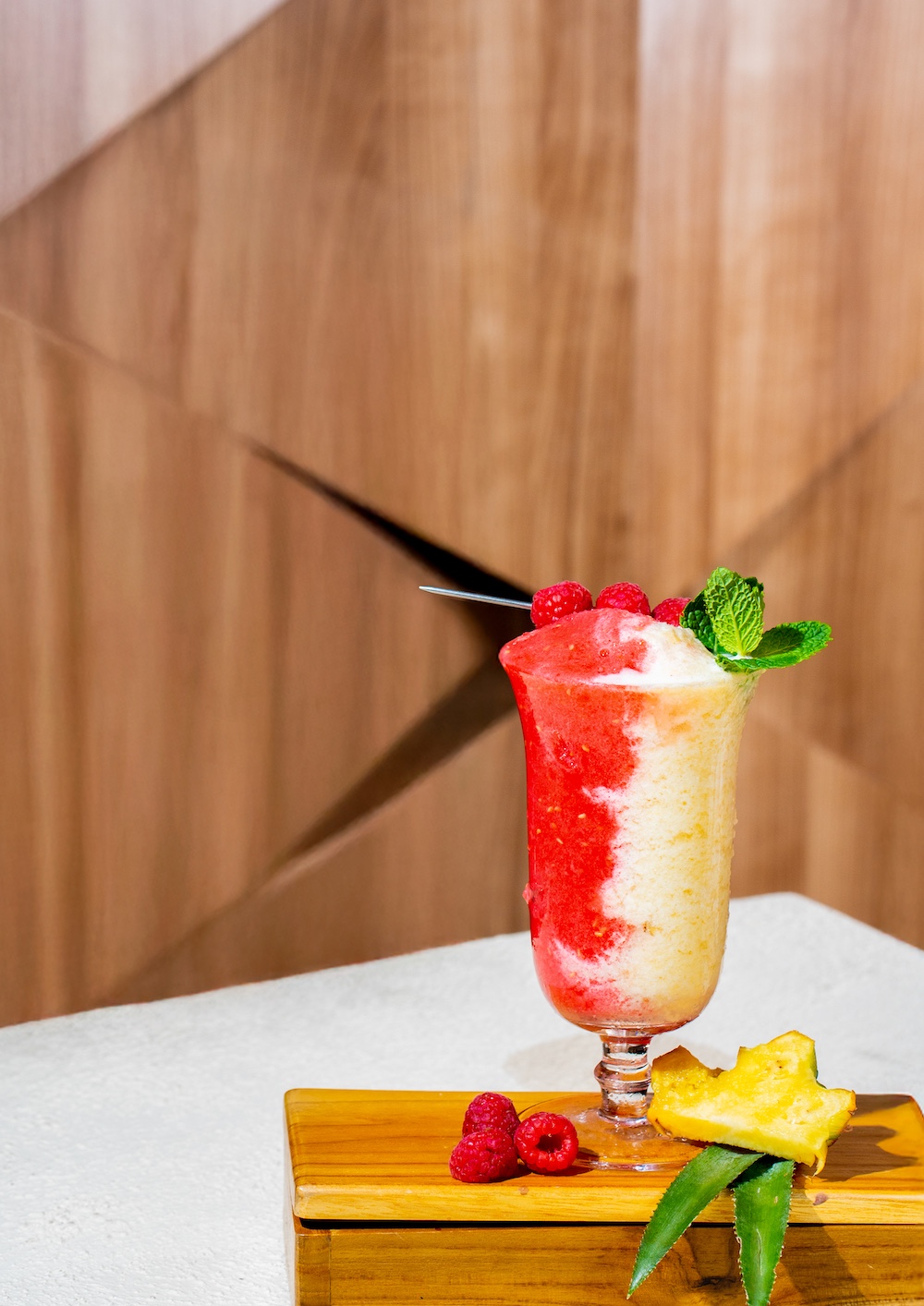 Sangsaka Smoothie menggunakan Denali Raspberry Puree dan Denali Pineapple Puree dengan garnish raspberry dan daun mint dalam Old Fashion Glass.